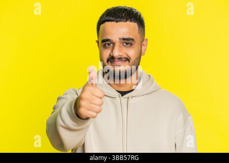 J'aime. L'homme indien lève les pouces est d'accord avec quelque chose ou donne une réponse positive recommande la publicité aime les bons commentaires d'idée, célébrant la victoire de succès. Gars hindou isolé sur fond jaune Banque D'Images