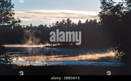 Le soleil levant brûle le brouillard au large du lac Little Bass dans le comté de Price, dans le nord du Wisconsin. Banque D'Images