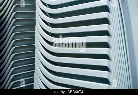 Gros plan de chaises de jardin en plastique blanc empilées formant un motif abstrait répété à la lumière naturelle. Banque D'Images