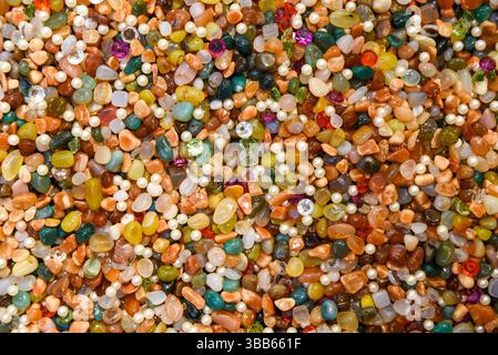 Fond coloré de pierres précieuses polies assorties, perles et cristaux. Texture brillante et vibrante de pierres naturelles mélangées et de perles de différentes formes Banque D'Images