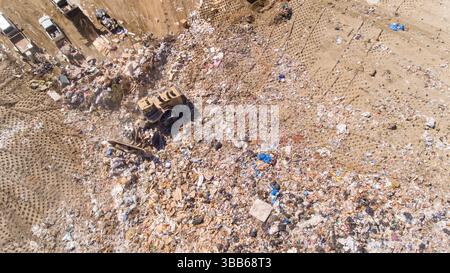Une grande benne à ordures est visible au milieu d'un tas de déchets Banque D'Images