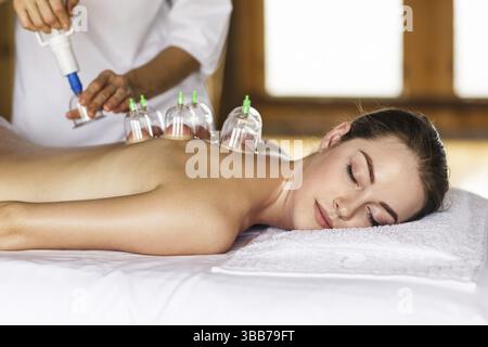 Femme allongée sur la poitrine avec traitement de cupping sur le dos Banque D'Images