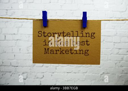 Storytelling est le meilleur texte marketing sur carte papier accrochée avec une corde sur fond de brique blanche Banque D'Images