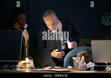 Les policiers enquêtant sur les lieux du crime examinant les preuves et la victime sur le bureau dans le bureau Banque D'Images