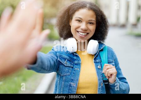 Joyeuse étudiante afro-américaine donnant High Five à un ami en plein air Banque D'Images