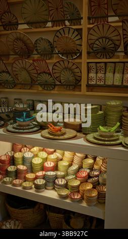 Des céramiques colorées exposées dans un magasin de poterie mettant en valeur des bols, des assiettes et des tasses vibrants disposés soigneusement sur les étagères, mettant en valeur l'artisanat artisanal Banque D'Images