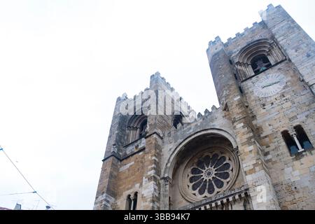 La cathédrale de Lisbonne, également connue sous le nom de se de lisboa, se dresse contre un ciel nuageux, mettant en valeur sa rose complexe, son horloge et son architecture fortifiée, un mélange de styles roman et gothique Banque D'Images