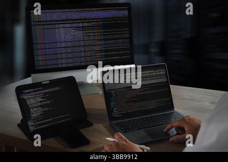 Une image de programmation de site Web montre une personne travaillant avec plusieurs dispositifs électroniques, y compris un ordinateur de bureau, un ordinateur portable et une tablette, tous affichés Banque D'Images