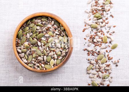 Mélange à collation de 5 graines, graines crues et noyaux dans un bol en bois sur lin. Graines de tournesol et de citrouille, graines de lin et de chia et graines de chanvre entier. Banque D'Images