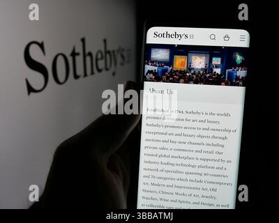 Stuttgart, Allemagne - 30 2024 : personne tenant un téléphone portable avec la page Web de la société britannique Sotheby's d'encanteur de luxe sur l'écran devant le logo. Banque D'Images