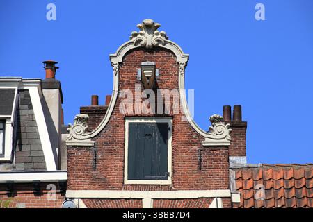 Façade de maison en briques historique avec cloche (ou horloge) décorée de près à Amsterdam, canal Prinsengracht, pays-Bas, mai 2025. Banque D'Images