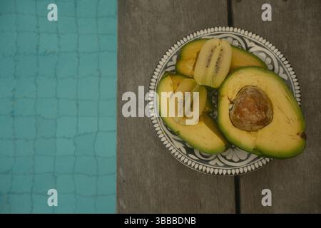 Une assiette d'avocat fraîchement tranché et kiwi doré près de la piscine Banque D'Images