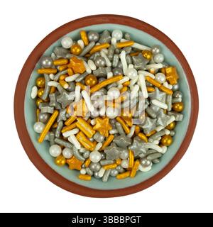 Vue de dessus d'un petit bol rempli de pépites festives sur le thème des fêtes sur un fond blanc. Banque D'Images