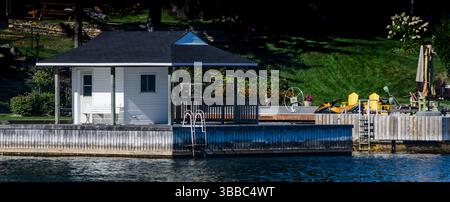Hangar à bateaux et chaises adirondack jaunes sur un quai par une journée ensoleillée Banque D'Images