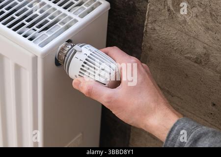 Main d'homme ajustant la température sur le radiateur de chauffage Banque D'Images