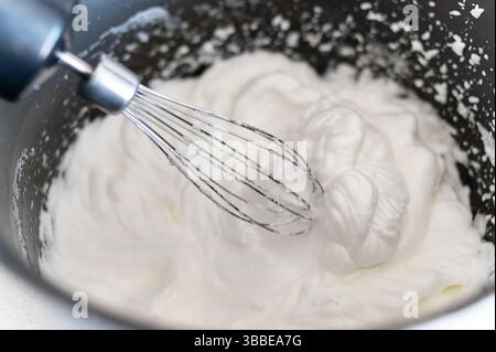 Gros plan du blender battant des blancs d'œufs pour faire de la meringue. Pâtisseries maison à partir de produits agricoles biologiques. Recette pour faire des desserts à la maison. Banque D'Images