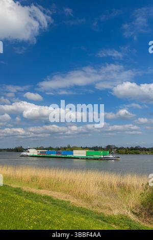 Cargo intérieur transportant des conteneurs sur la rivière Lek près de Lopik à Utrecht, pays-Bas, sous un ciel bleu avec des nuages blancs Banque D'Images