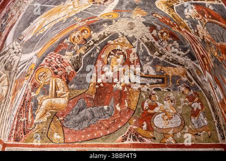 Une fresque vibrante de la Nativité décore l'église Carikli à Goreme, représentant Marie, Joseph et Christ dans une scène biblique détaillée de naissance. Banque D'Images