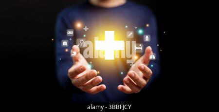Concept de santé et d'assurance maladie. Un homme tenant le symbole de la croix de santé avec des icônes Banque D'Images