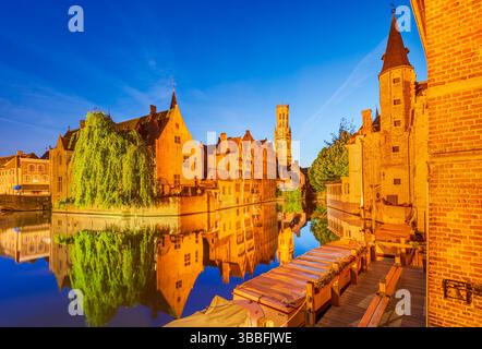 Bruges, Belgique. Le crépuscule baigne Rozenhoedkaai dans des teintes dorées, reflétant le charme médiéval sur les eaux tranquilles du canal de Bruges. Banque D'Images