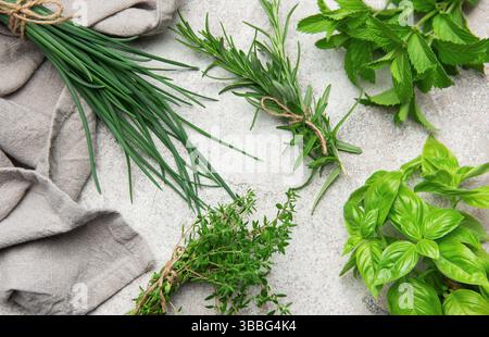 Grappes d'herbes fraîchement récoltées disposées sur une table grise, prêtes à être utilisées pour la cuisson ou la garniture Banque D'Images