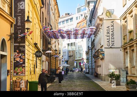 Slovaquie, Bratislava - 8 octobre 2022 : une rue étroite avec des parapluies suspendus dans la vieille ville de Bratislava Banque D'Images