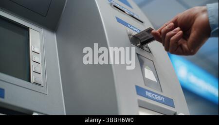 Distributeur automatique de billets dans le terminal de l'aéroport : personne méconnaissable insérant la carte de crédit en plastique dans la fente du lecteur de carte pour la transaction de retrait d'espèces. Guichet automatique, services bancaires. Gros plan. Banque D'Images