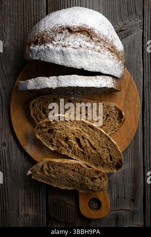 Vue de dessus sur des tranches de pain appétissantes de levain au levain sur une planche de bois rustique. Gros plan sur un pain artisanal de style ferme Banque D'Images