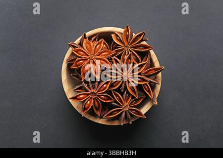 Étoiles d'anis aromatiques dans un bol sur une table sombre, vue de dessus Banque D'Images