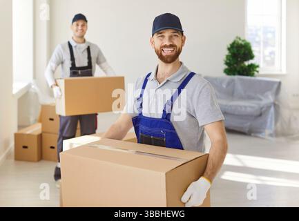 Hommes heureux ouvriers du service d'enlèvement transportant des boîtes en carton emballées Banque D'Images