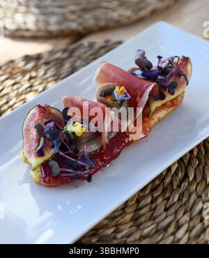 Bruschetta savoureuse au prosciutto et figues sur plaque blanche Banque D'Images
