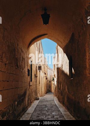 Rue pavée étroite illuminée par la lumière du soleil dans une ville historique Banque D'Images