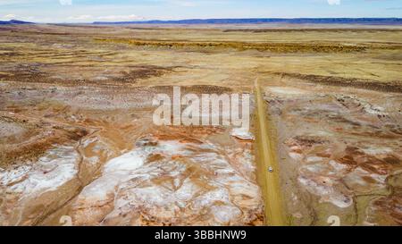 Vue aérienne d'une camionnette sur un chemin de terre traversant un terrain désertique coloré Banque D'Images