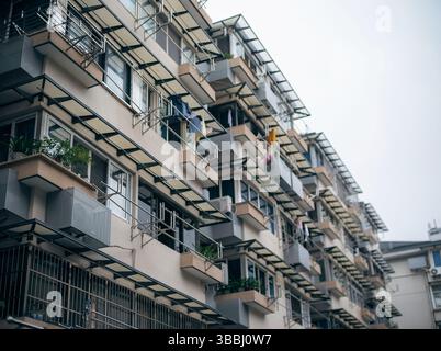 Façade avec balcon du bloc résidentiel de Hangzhou avec casiers de séchage, plantes en pot et auvents, Zhejiang, Chine Banque D'Images