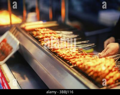 Brochettes de viande grillée dorée rôtissant sur flamme nue dans un stand Street Food BBQ Banque D'Images