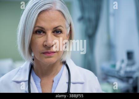 Médecin de femme senior debout portant une blouse de laboratoire blanche et stéthoscope dans la salle de clinique Banque D'Images