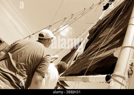 Deux garçons levant la voile à bord du grand voilier Jolly Rover accostent sur le bord de la rivière à Georgetown, Caroline du Sud, États-Unis. Banque D'Images