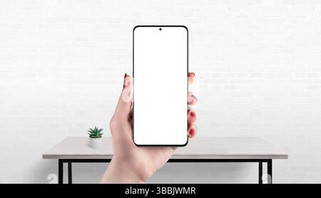 Maquette de smartphone à la main avec écran isolé, bureau en arrière-plan, idéal pour présenter une application, un site Web ou une boutique en ligne Banque D'Images