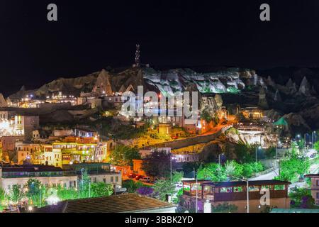La vue nocturne de Goreme Cappadoce révèle des maisons illuminées et des formations rocheuses qui brillent sous le ciel sombre de la vallée. Banque D'Images