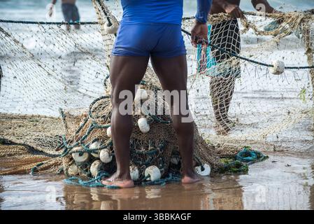 Un demi-corps de pêcheurs non identifiés ramassant le filet de pêche après avoir capturé du poisson. Fruits de mer, pêche comme passe-temps. Brésil Banque D'Images