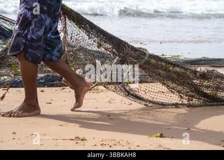 Un demi-corps de pêcheurs non identifiés ramassant le filet de pêche après avoir capturé du poisson. Fruits de mer, pêche comme passe-temps. Brésil Banque D'Images