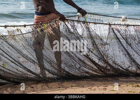 Demi-corps d'un pêcheur non identifié tirant un filet de pêche. fruits de mer, passe-temps. Brésil Banque D'Images