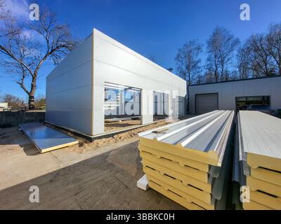 Bâtiment industriel préfabriqué en construction. Châssis en acier et panneaux sandwich isolés installés sur le site Banque D'Images
