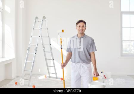 Peintre souriant au travail pendant la rénovation de la maison Banque D'Images