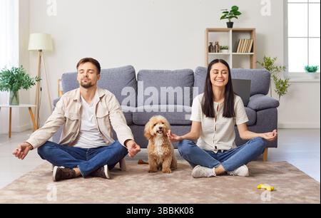 Couple de famille heureux méditant avec chien à la maison Banque D'Images
