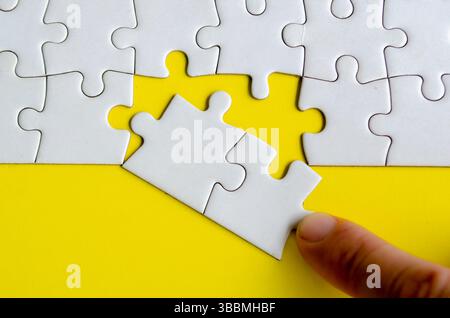 Main plaçant les puzzles manquants. Un concept simple mais puissant de pièces de puzzle représentant l'unité de solutions et la connexion délibérée. Banque D'Images