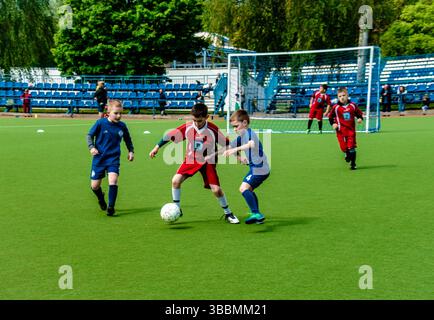Les enfants jouent au football sur une pelouse verte. Enfants qui font jouer le ballon de football. Groupe de garçons heureux, mode de vie actif et sain, jeux d'enfance Banque D'Images