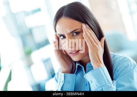 Femme professionnelle dans un cadre de bureau semblant réfléchi et concentré dans une tenue formelle d'affaires Banque D'Images