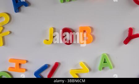 Travail de lettres magnétiques colorées sur un tableau blanc à cadre en bois dans la salle de classe ou la salle de jeux. Banque D'Images