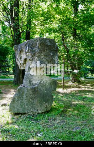 Une sculpture en pierre frappante ressemblant à une tête se trouve bien en vue dans un parc animé rempli d'arbres verts pendant la journée. Filtre la lumière du soleil à travers t Banque D'Images